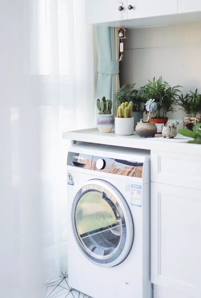 white front load Electric Dryer beside white wooden cabinet drying clothes